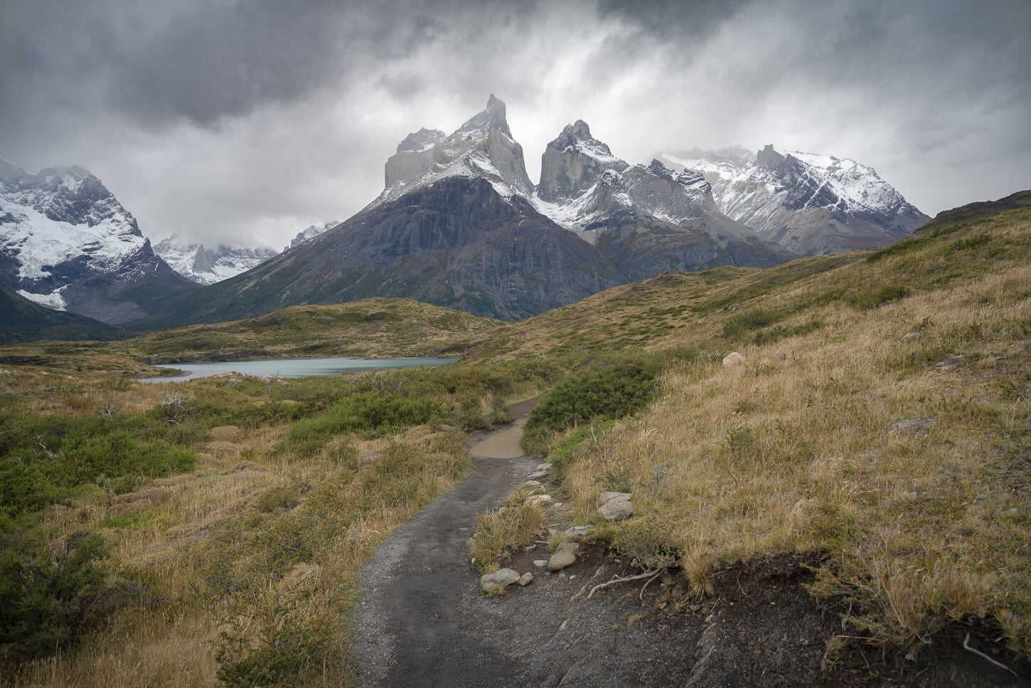 Hiking trail in torres del paine with view of the Cuernos under a dark sky typical of patagonia