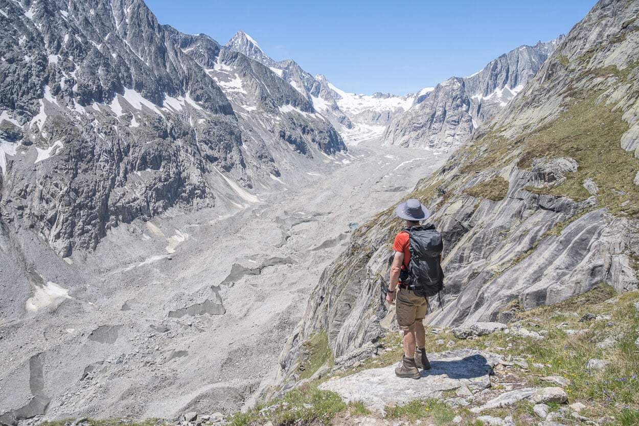 Hiker with an Osprey talon 44 backpack looking at an alpine landscape on a sunny day.