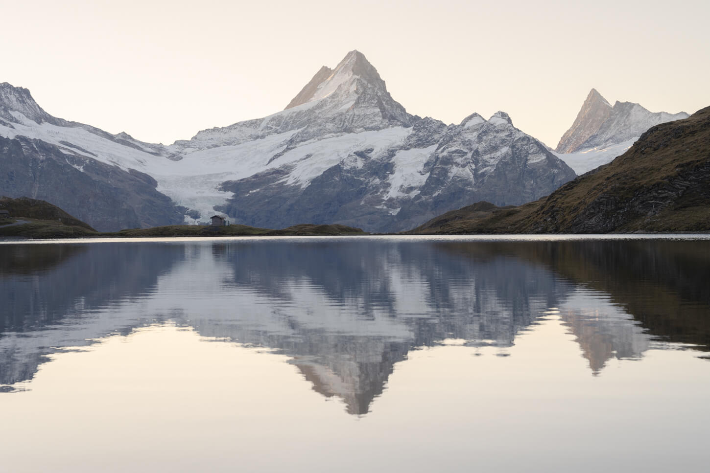 Mount Schreckhorn reflecting in Bachalpsee at Sunrise, under a warm, cloudless sky 