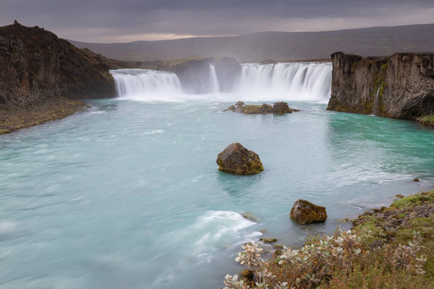 Horseshoe shaped waterfall in north iceland on a cloudy day, which enhances the blue color of the water.