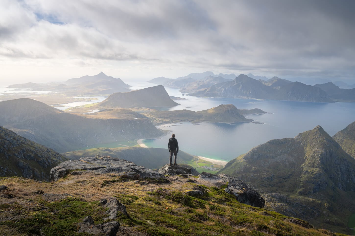View from Himmeltinden in the Lofoten, with a hiker looking at the landscape diring the hike