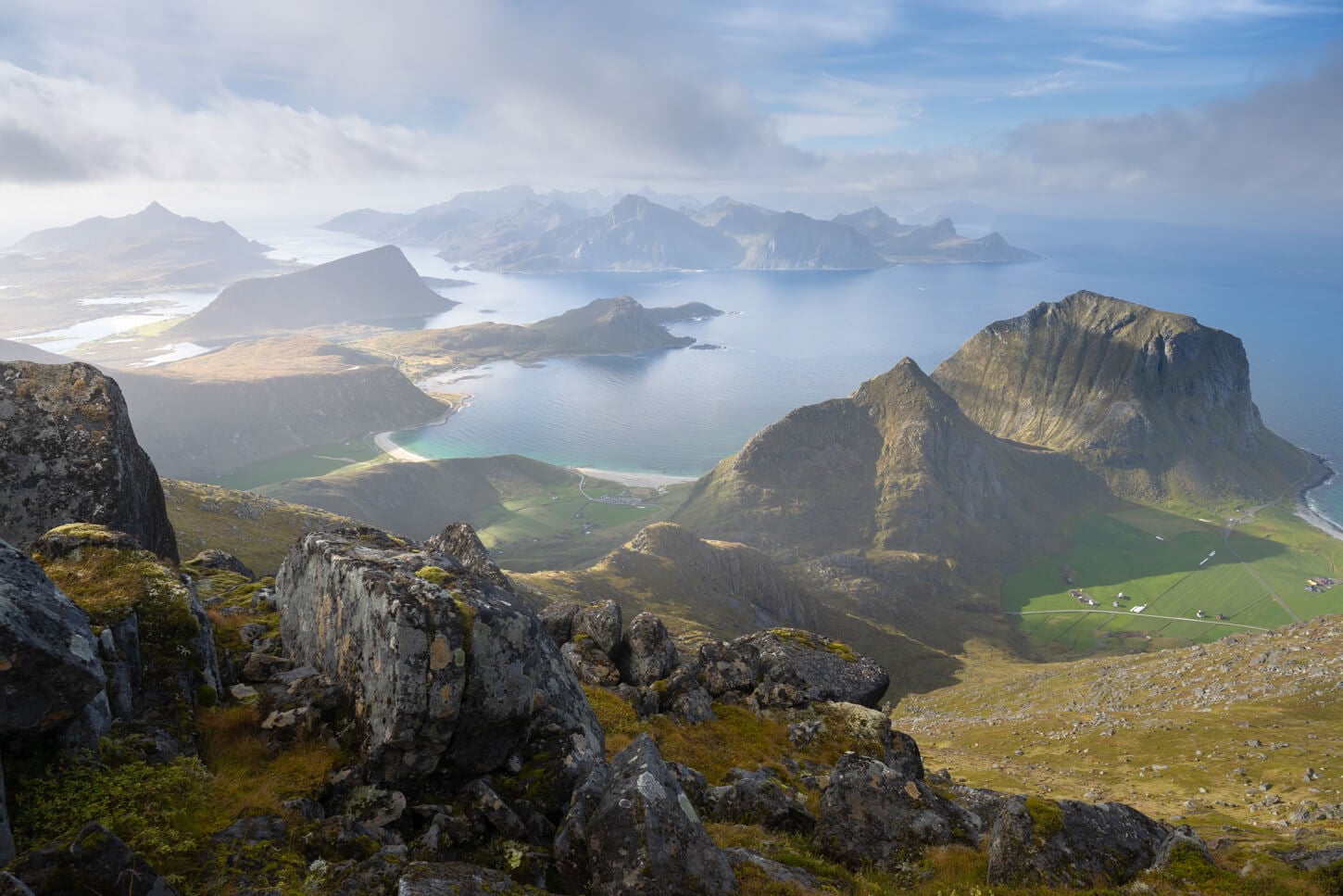 View of the landscape from Himmeltinden mountain in the Lofoten, with soft light clearing the clouds