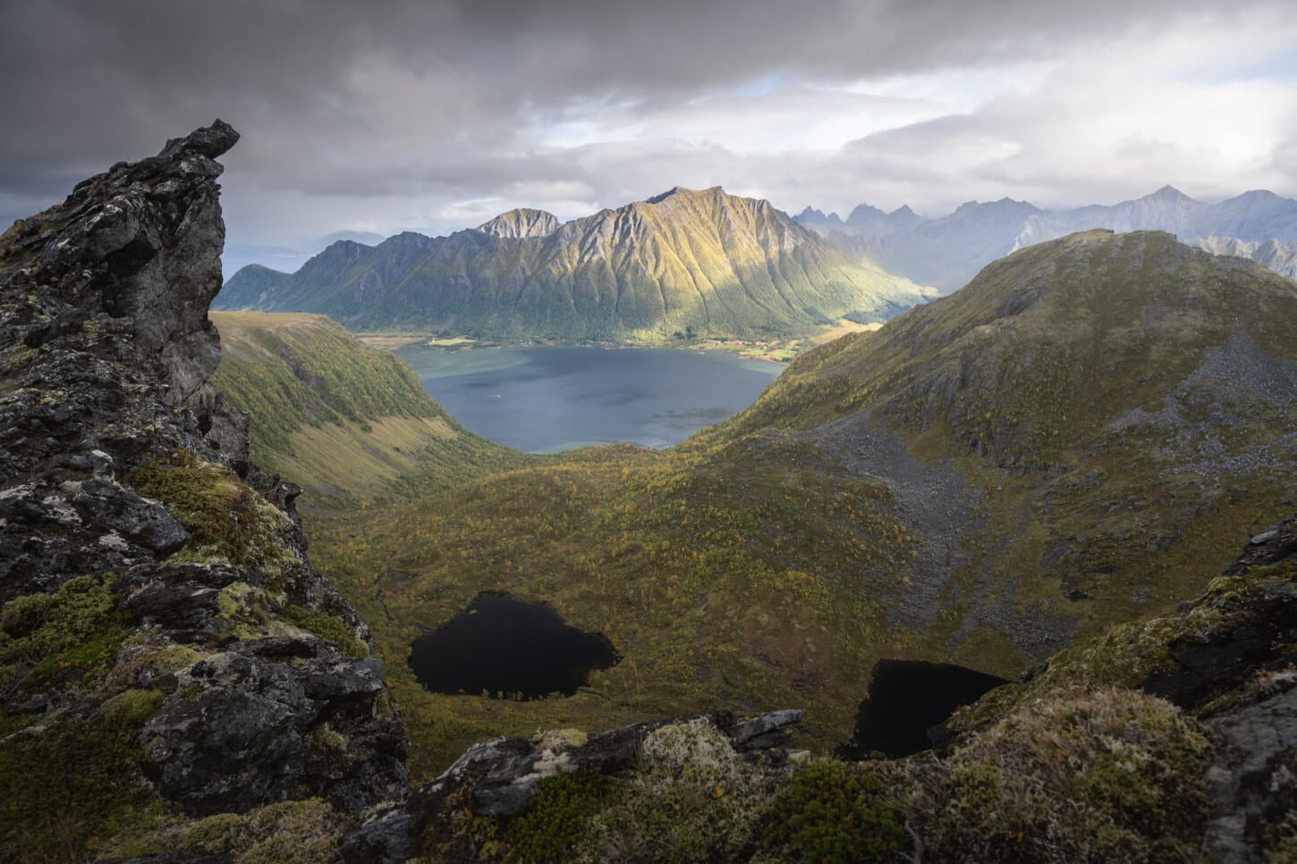 Grunnførfjorden viewed from the ridge trail to Matmora, under a dark sky with warm sideling coming from the right