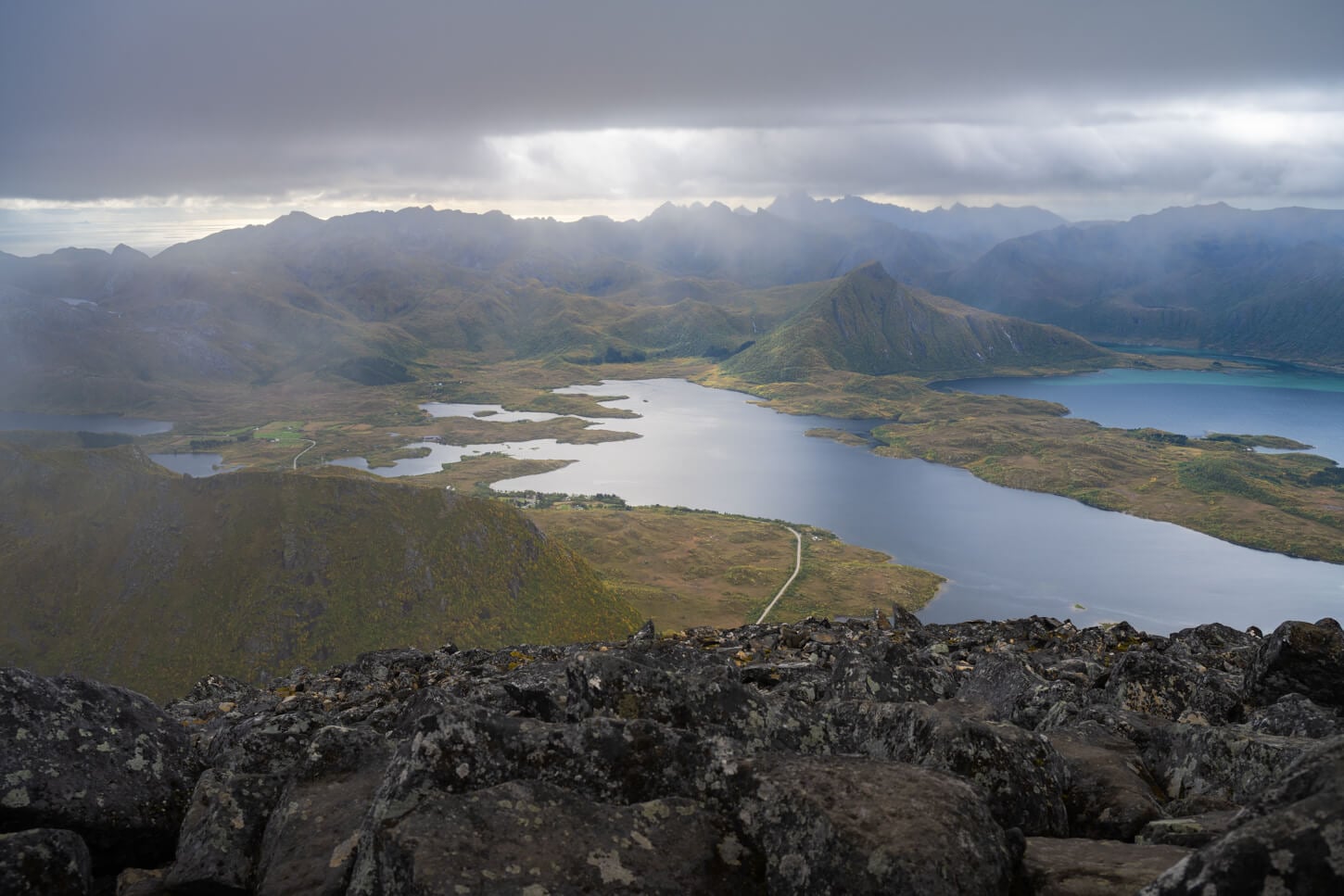 View of the landscape from Matmora's summit at the end of the hike, with multiple layers of mountains in the distance, under a partly cloudy dramatic sky.