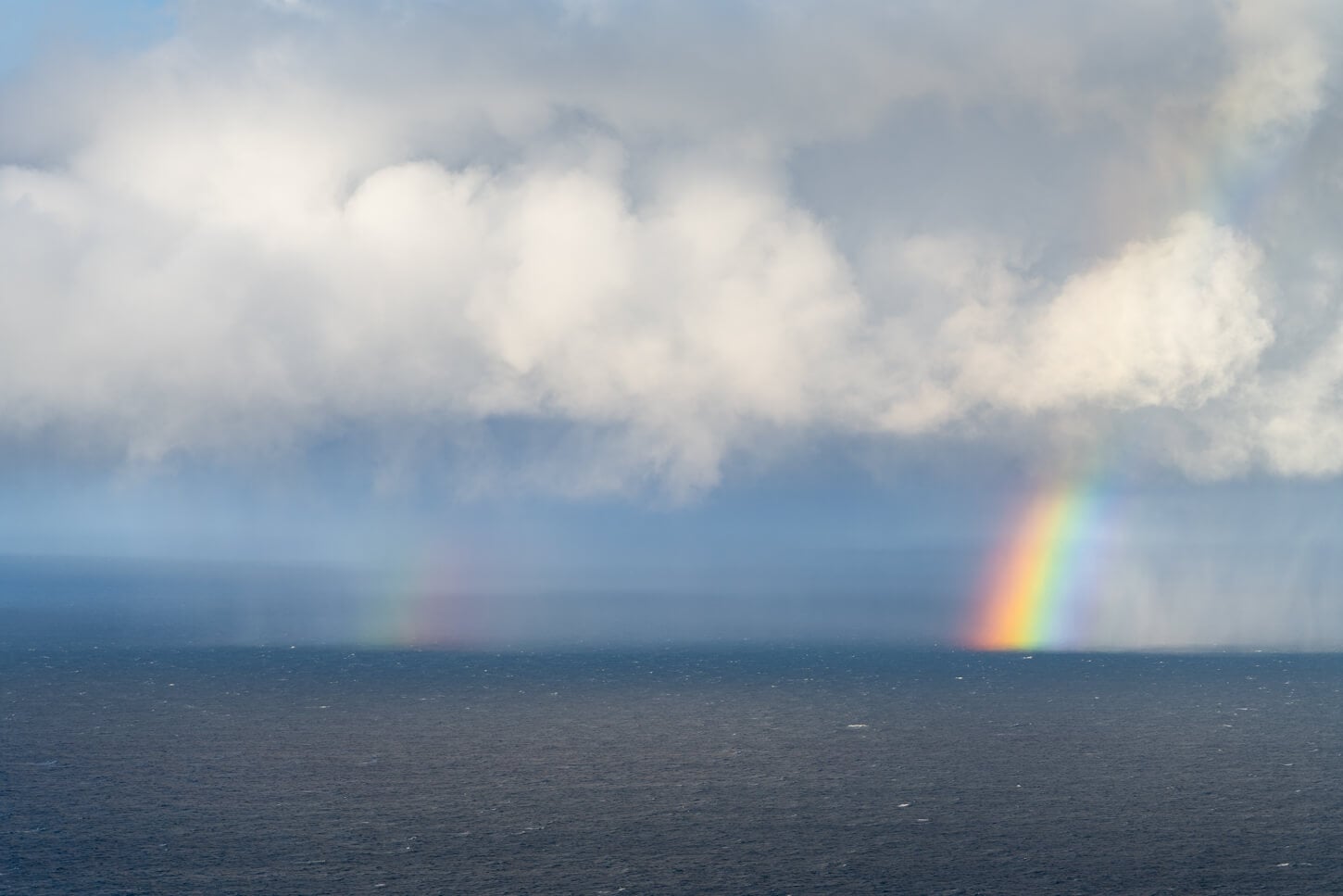 View of the arctic ocean from North Cape, with clouds and rainbows passing above the water