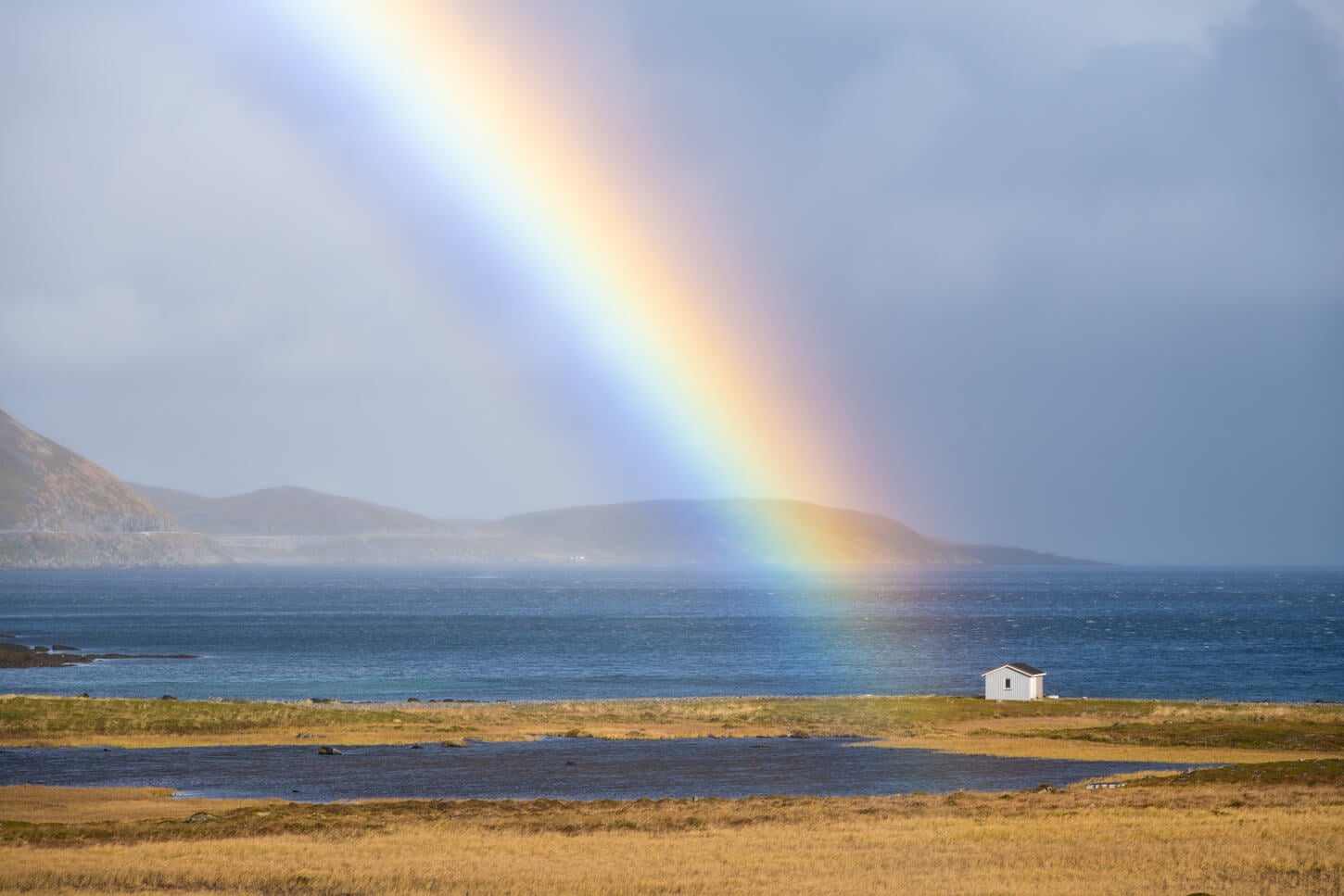 Rainbow ending next to a small hut on the acric coast of Northern Norway