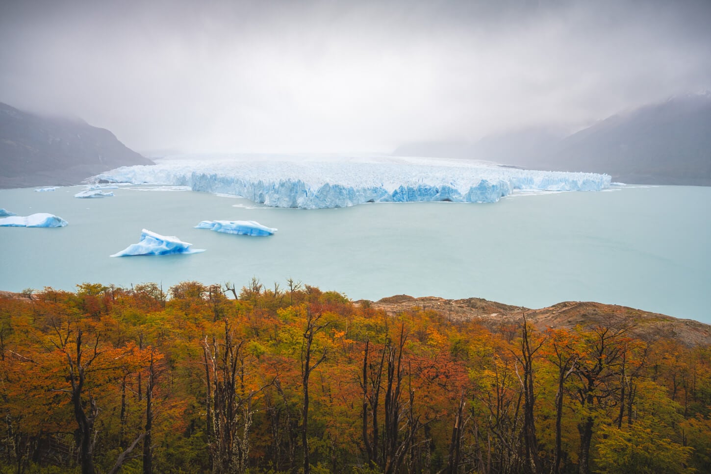 Perito moreno glacier in Autumn under a grey sky with low hanging clouds on a rainy day