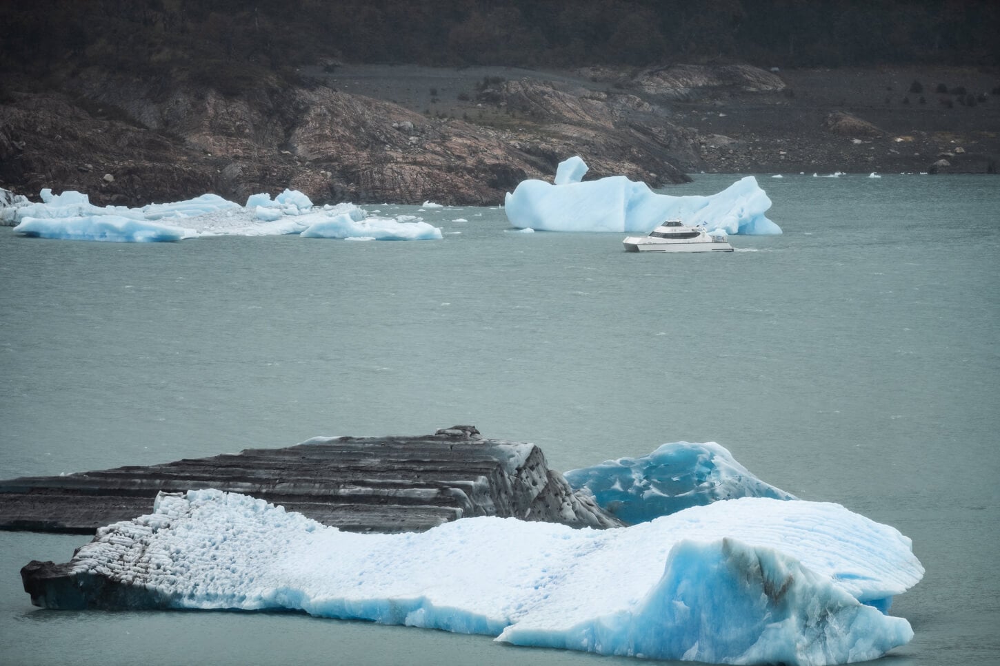 Boat next to some icebergs in a lake in argentinian patagonia