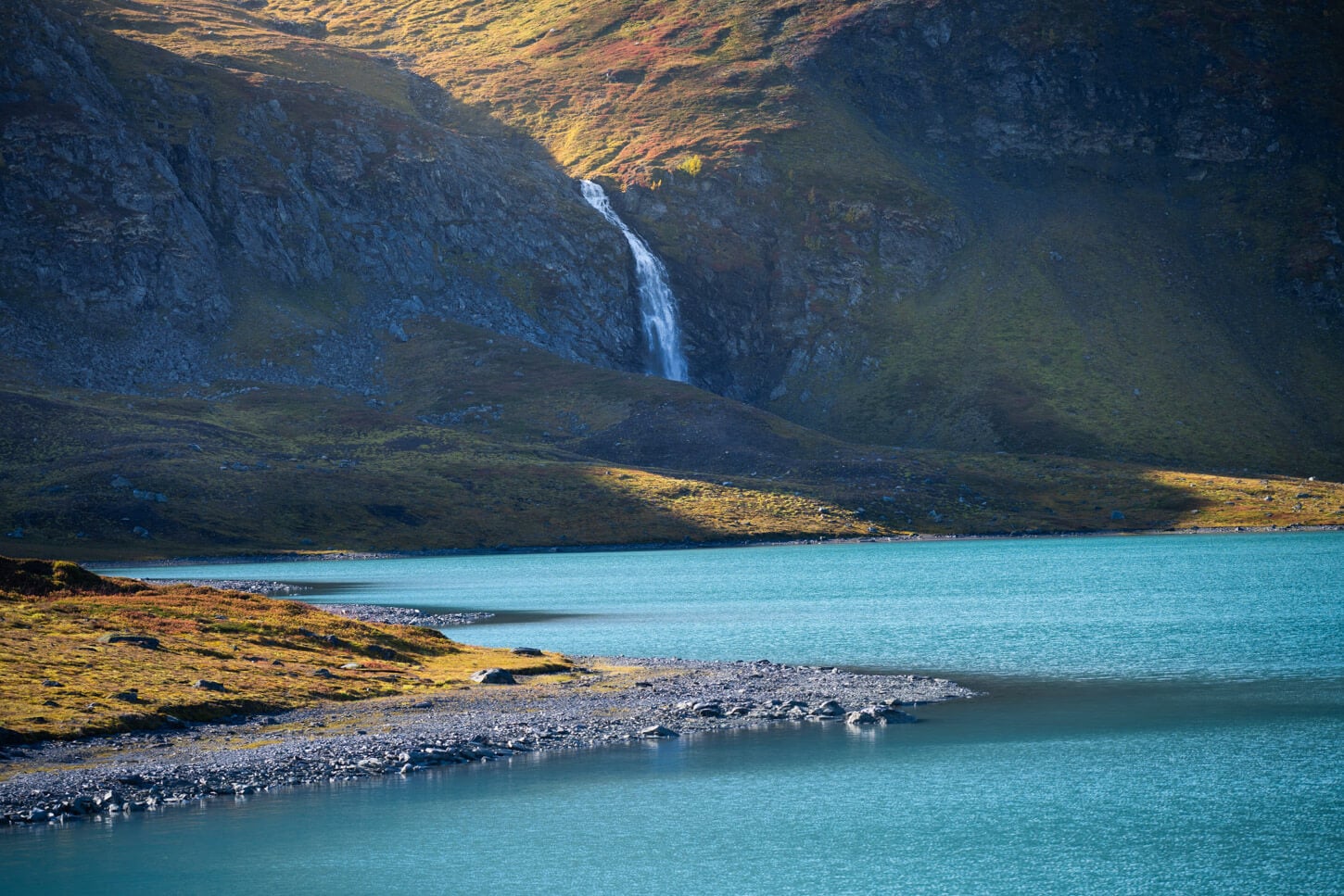 Waterfall in the Lyngen alps cascading into a turquoise lake