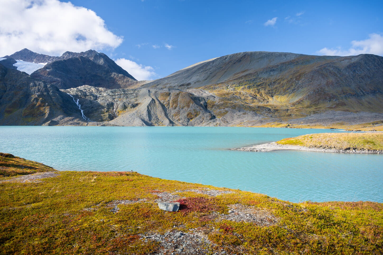 View of the Rottenvikvatnet Lake in the Lyngen Alps on a sunny autumn day with vibrant colors