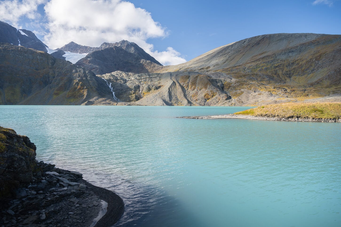 Lake with blue colors in the Lyngen Alps and a glacier in the background.