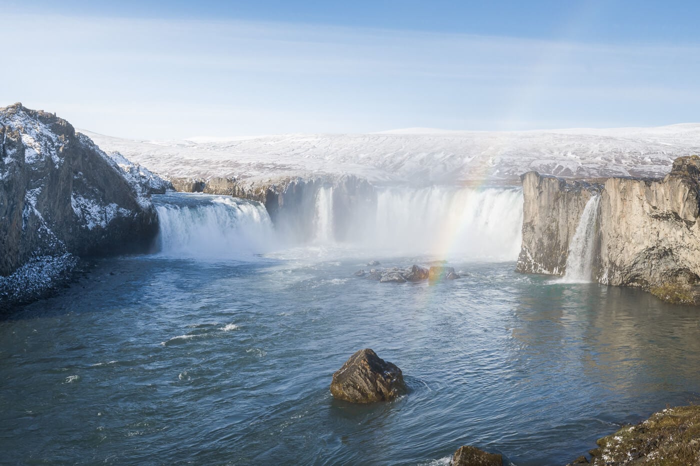 Waterfall in north iceland with a faint rainbow visible across the waterfall.